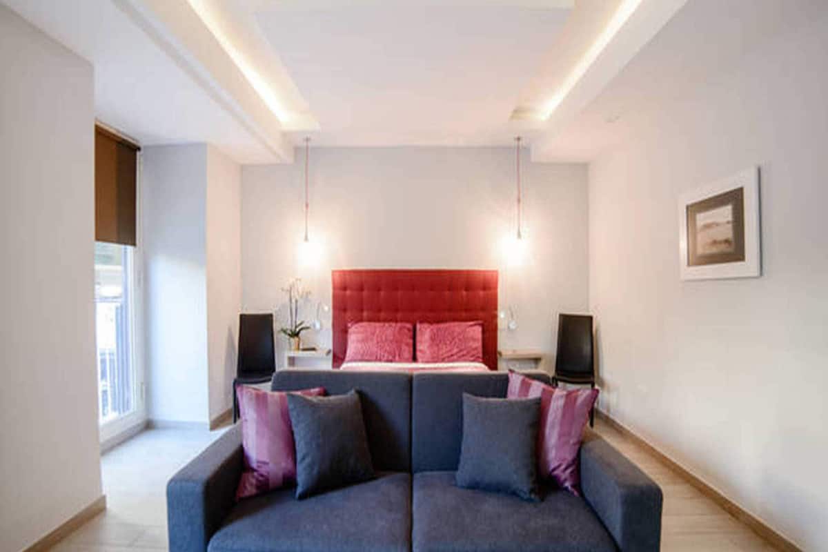 Une chambre moderne avec un grand lit, un canapé bleu et deux haut-parleurs.