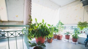 Ein Balkon mit Topfpflanzen, einem Metallgeländer und einem gefliesten Boden.