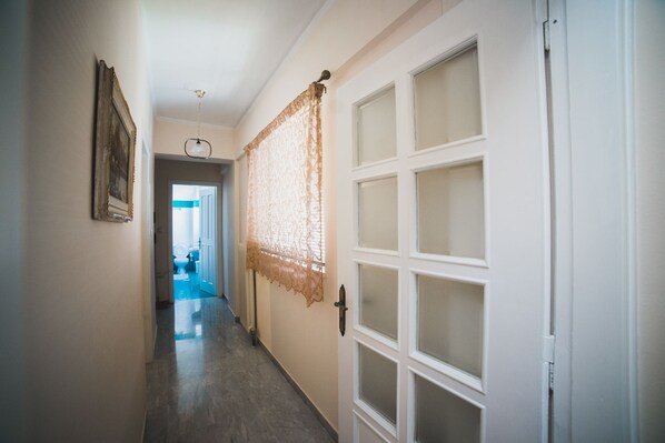 A hallway with a door on the right, a framed picture on the left, and a glimpse of a bathroom in the background.