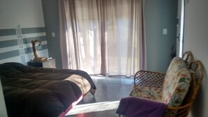 A bedroom with a bed, a nightstand, a chair, and a window with curtains. - Casita del Sauce (Sierra de la Ventana)