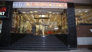 De ingang van Hotel Al Harmain Tower, met een bord boven de ingang en een trap naar de lobby.