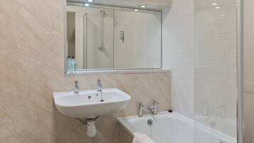 A bathroom with a sink, mirror, and bathtub.