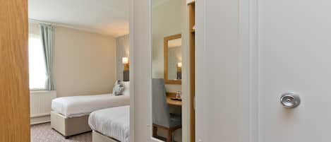 Habitación de hotel con cama, mesita de noche, una silla y un espejo.