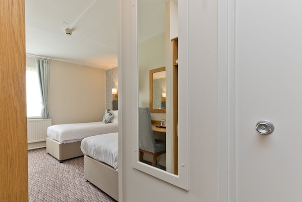 Habitación de hotel con cama, mesita de noche, una silla y un espejo.