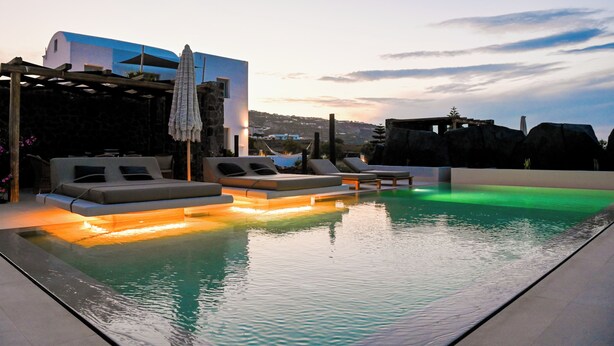 A rooftop pool area with lounge chairs and a pergola. - Saint Apostles (Santorini)