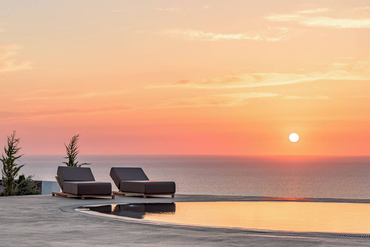 Vista al tramonto con due poltrone da relax e una piscina.