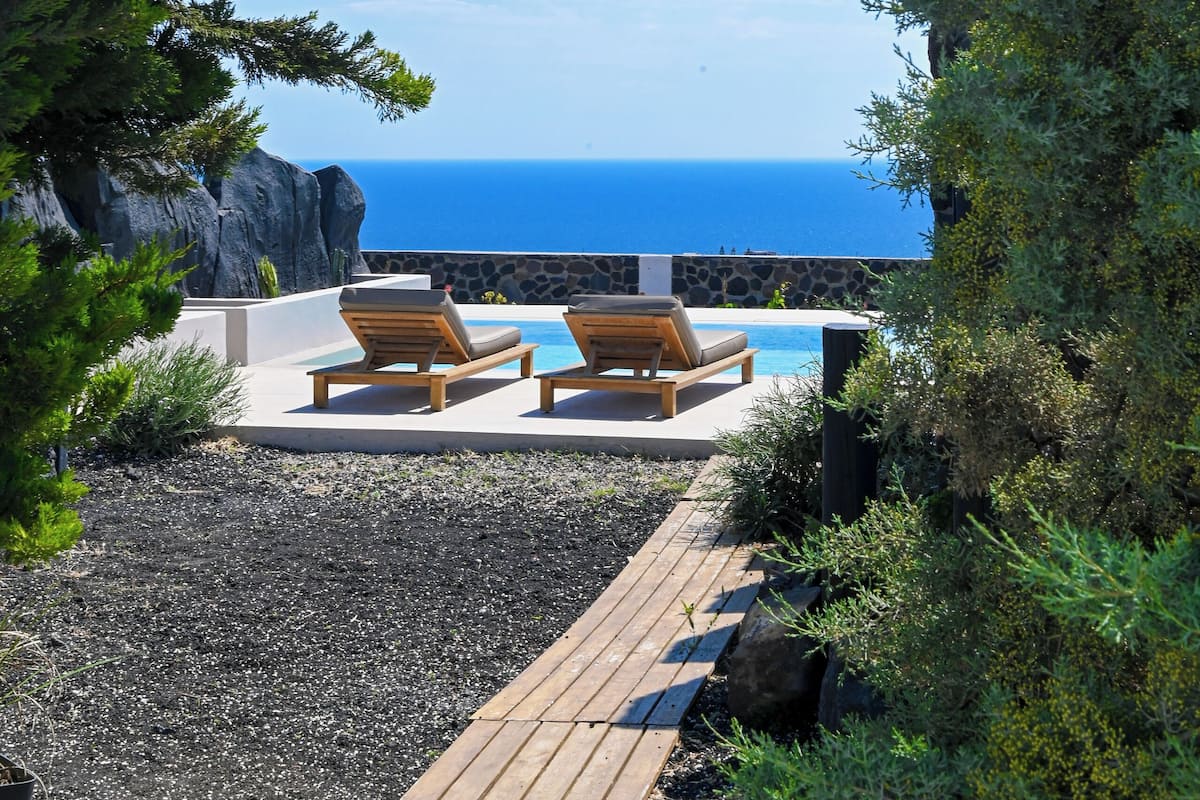 Un terrazzo in legno con due poltrone vista piscina e mare.