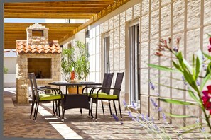 An outdoor patio with a stone fireplace, wicker chairs, and a tiled floor. - Villas Almar (Dobrinj)