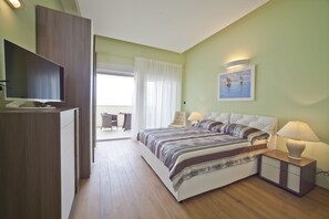 A bedroom with a bed, bedside tables, a TV, and a painting on the wall. - Villas Almar (Dobrinj)