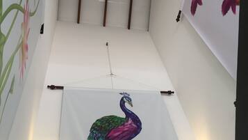A room with a large peacock mural on the wall, a ceiling with wooden beams, and a light fixture.