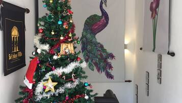 Un árbol de Navidad adornado con adornos y una estrella en la parte superior, una pintura de un pavo real y un cuadro enmarcado con flores.