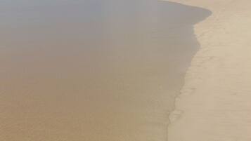 Una playa arenosa con olas suaves lamiendo la orilla.