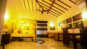 A room with a bed, a dining table, chairs, a sofa, and a ceiling fan. - Sri Lankan Villa (Koggala)