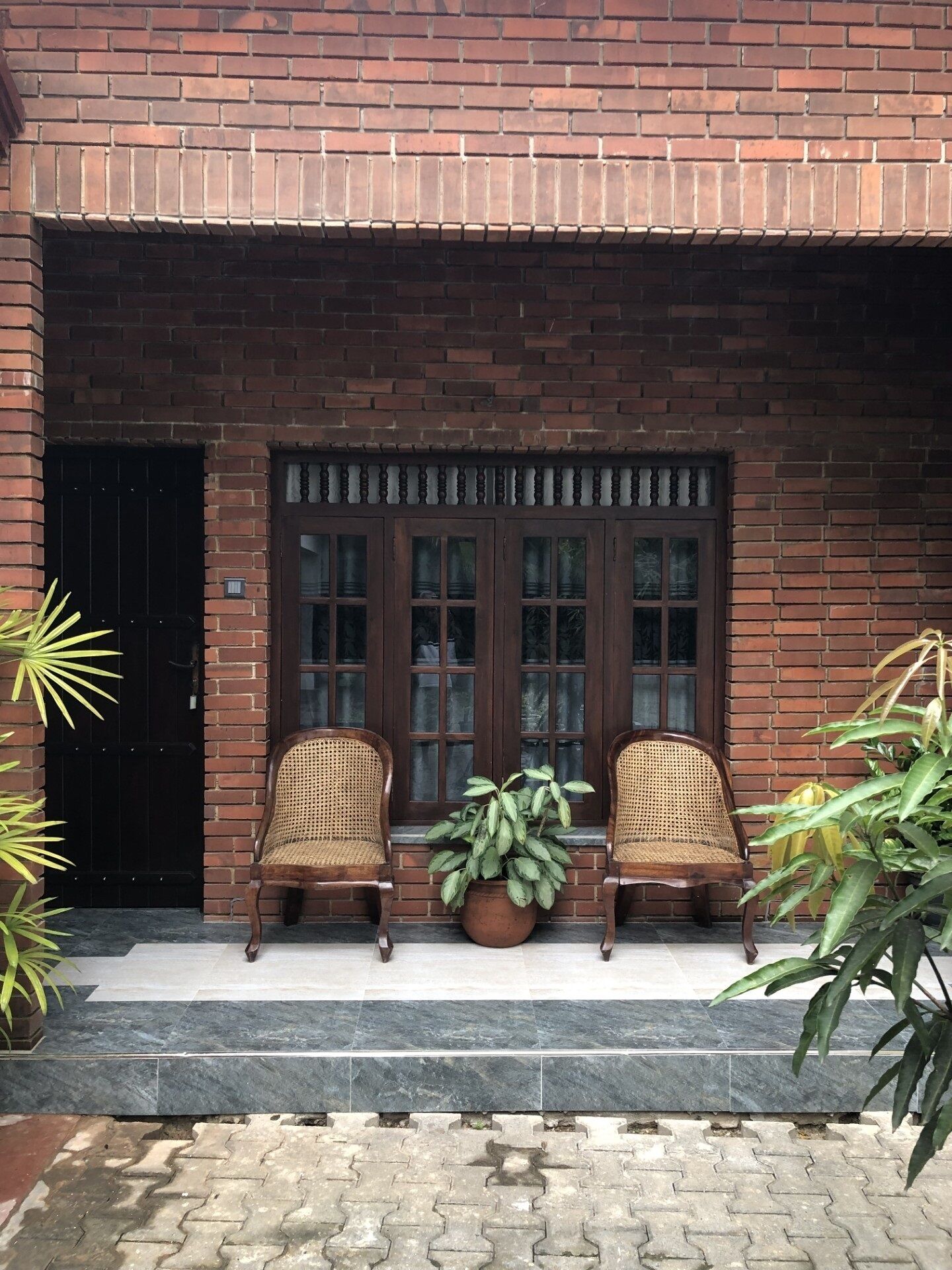 A brick building with a double door and two wicker chairs in front.