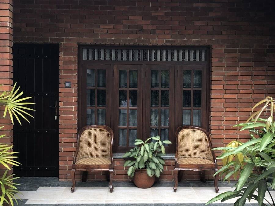 A brick building with a double door and two wicker chairs in front.