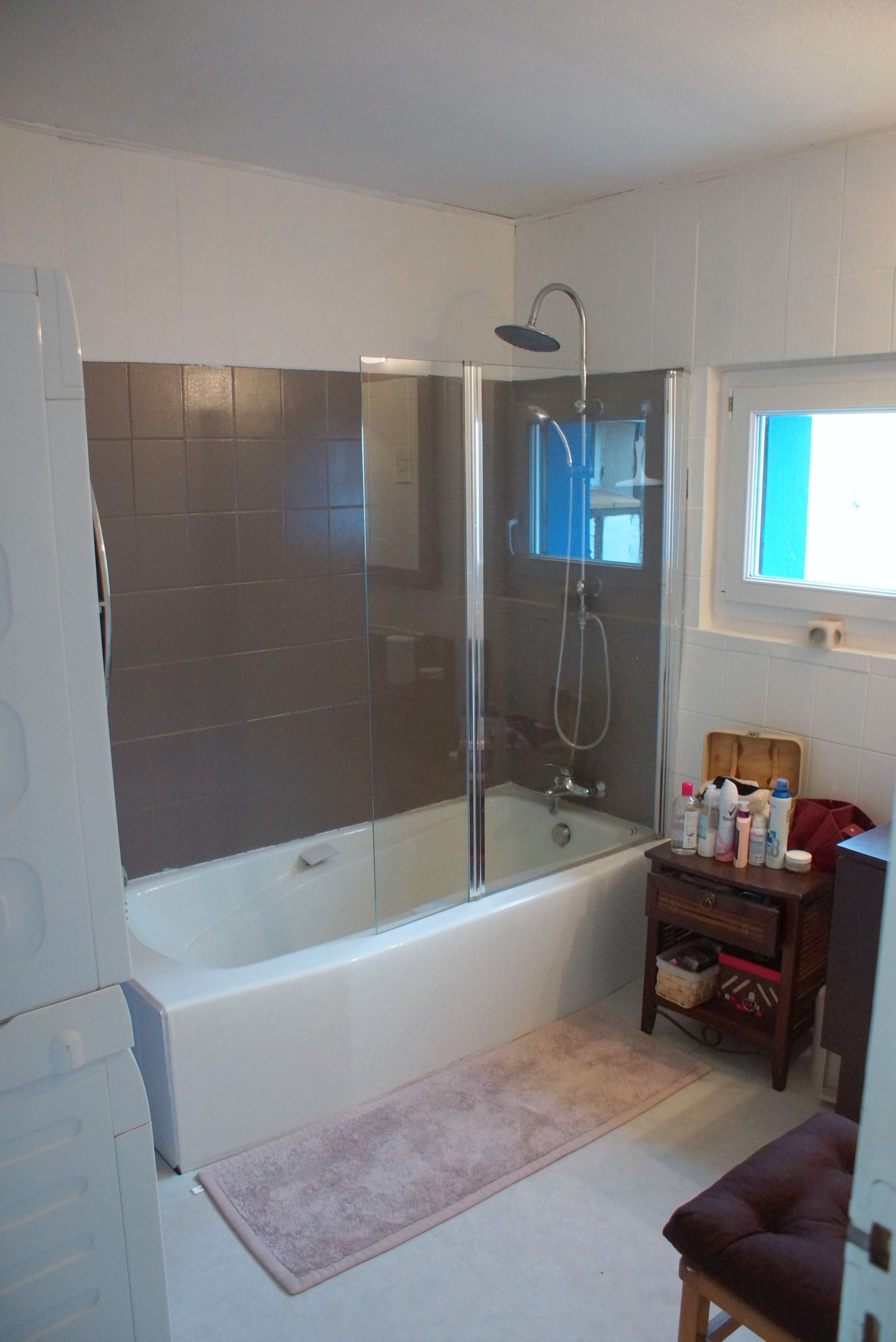 A bathroom with a glass-enclosed shower, a bathtub, and a vanity with toiletries.