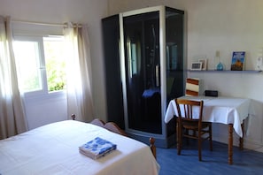 A room with a bed, a chair, a desk, and a shelf with books and a bottle. - La Bretonnière Longère Picarde (Passel)