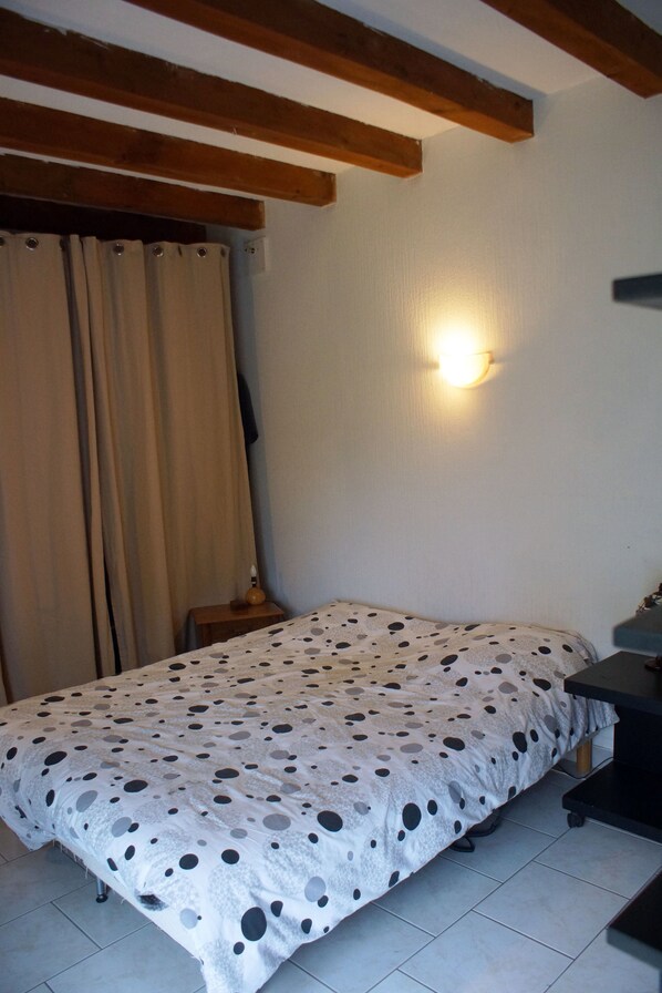 Un dormitorio con cama, mesita de noche, lámpara y luz empotrada en la pared.