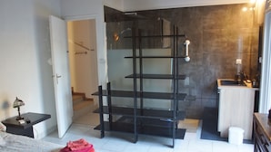 Uma casa de banho moderna com cabine de duche em vidro, lavatório encastrado e toucador pequeno.