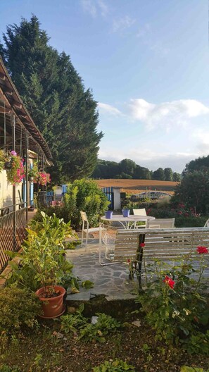 A rustic outdoor seating area with a wooden table and chairs, surrounded by potted plants and flowers. - La Bretonnière Longère Picarde (Passel)