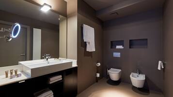 Un baño moderno con un espejo grande, dos lavamanos, un inodoro y un bidé.