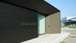 A modern hotel facade with a dark exterior and a clear sign reading "delparco hotel". - Delparco Hotel (Buttrio)
