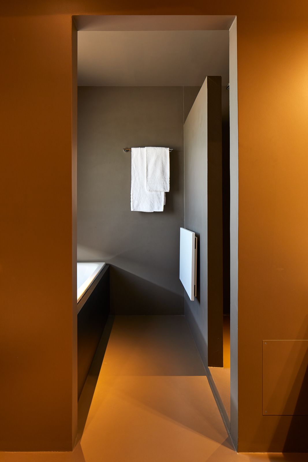 Une petite salle de bain moderne, avec une serviette suspendue à un porte-serviettes, un miroir et un éclairage encastré.