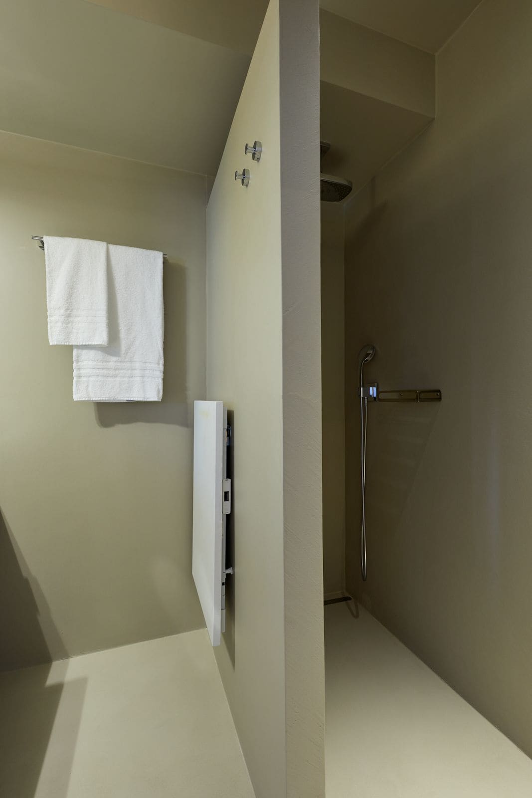 A modern bathroom with a shower, a towel rack, and a white cabinet.