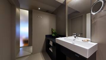 A modern bathroom with a white sink, black vanity, and a large mirror.
