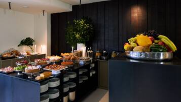A buffet setup with various food items and a fruit bowl.