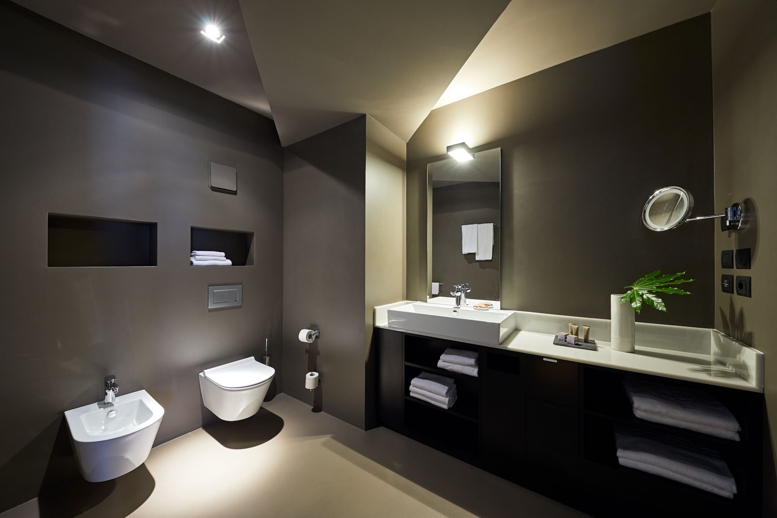 Ein modernes Badezimmer mit Waschbecken, Toilette und großem Spiegel.