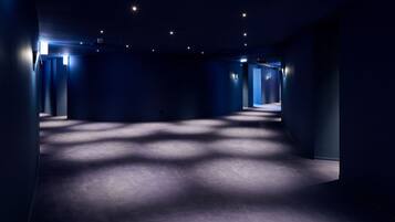 Ein schwach beleuchteter Flur mit weichem Teppich, Wänden mit integriertem Licht und einer Decke mit gleichmäßig verteilten Leuchten.