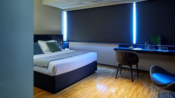 Un dormitorio moderno con cama, escritorio, silla y un vaso de agua sobre una mesa.