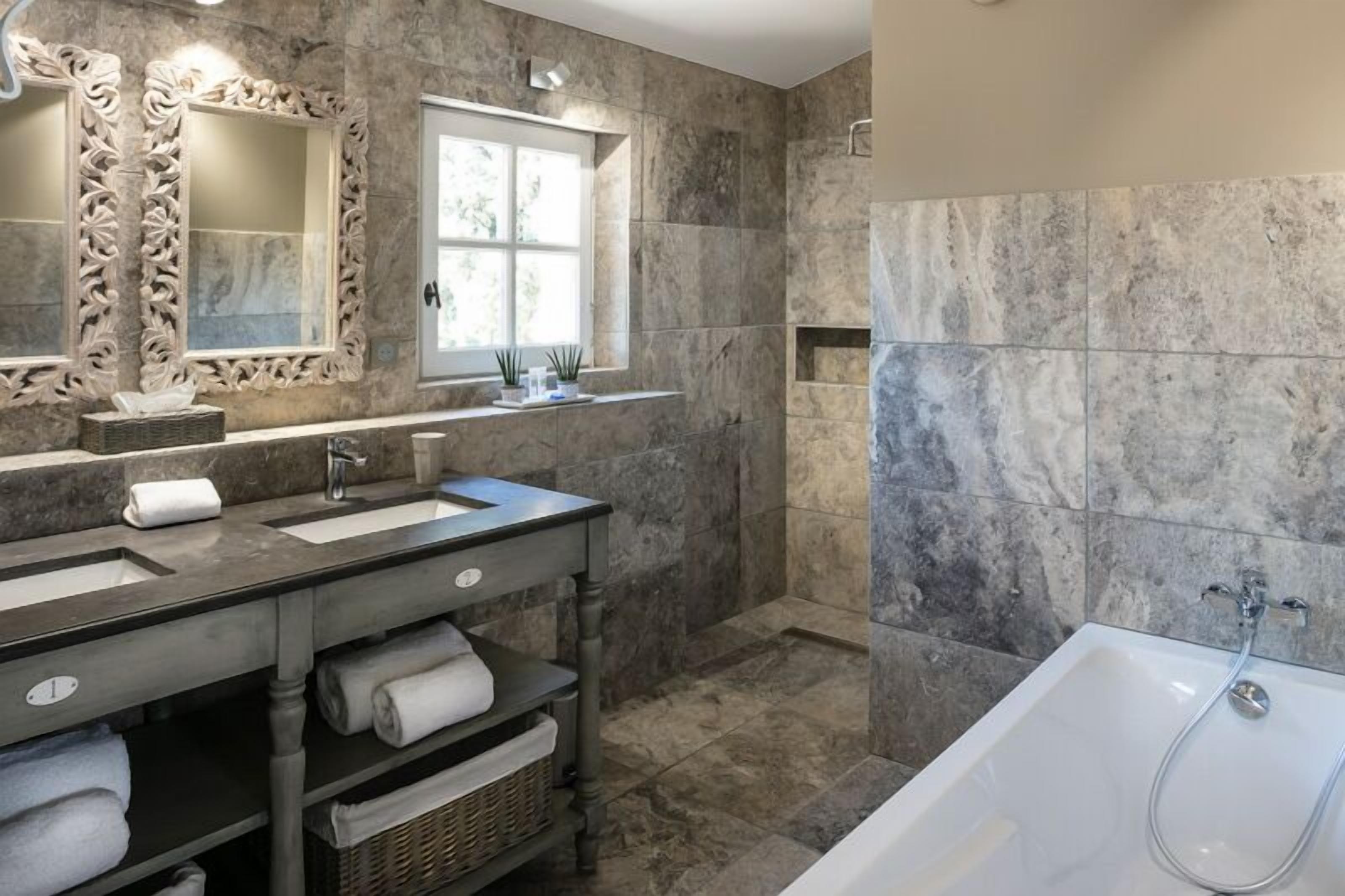 Un baño con dos lavamanos, un espejo grande, una ventana y una bañera.