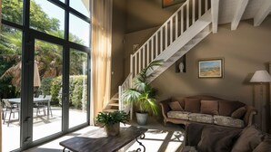 Un espacio habitable amplio con un gran ventanal, una escalera, un sofá y una mesa con una planta.