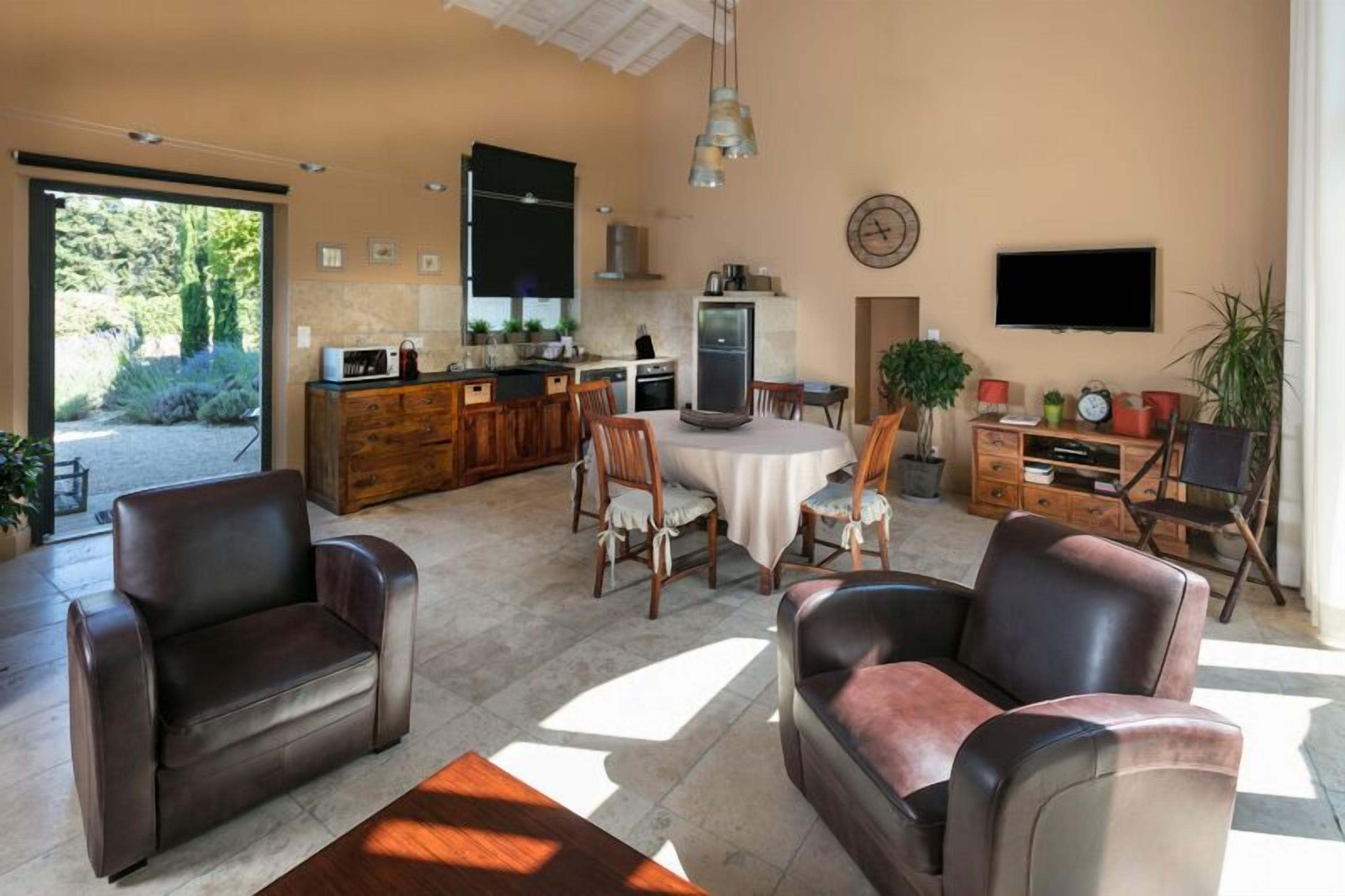 A spacious living area with leather sofas, a dining table, and a kitchen in the background.