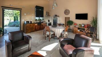 A spacious living area with leather sofas, a dining table, and a kitchen in the background.