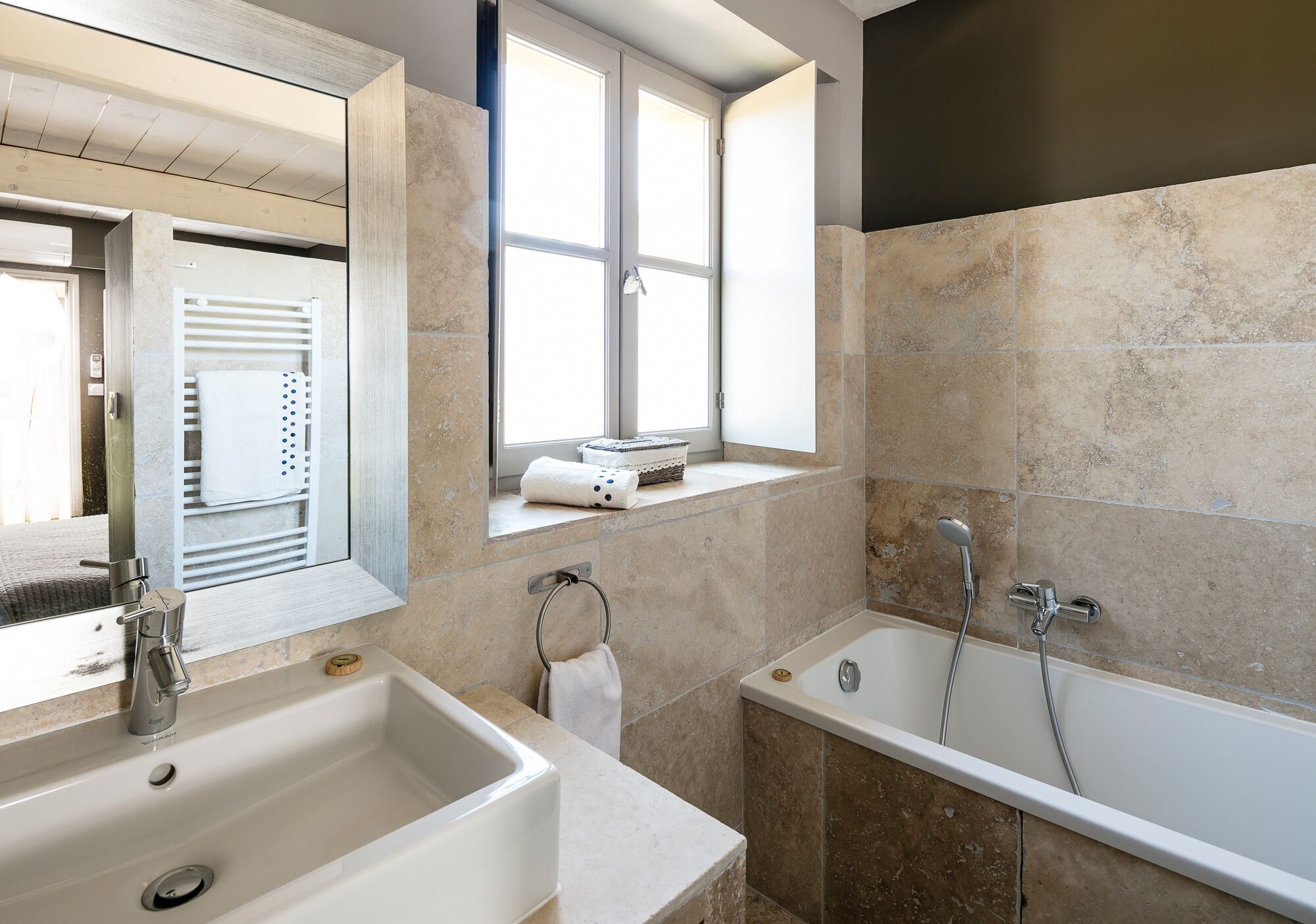 Ein modernes Badezimmer mit einem großen Waschbecken, einer Badewanne und einem Fenster mit Handtuchhalter.