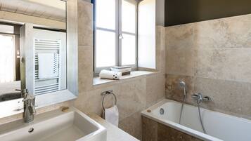 Ein modernes Badezimmer mit einem großen Waschbecken, einer Badewanne und einem Fenster mit Handtuchhalter.