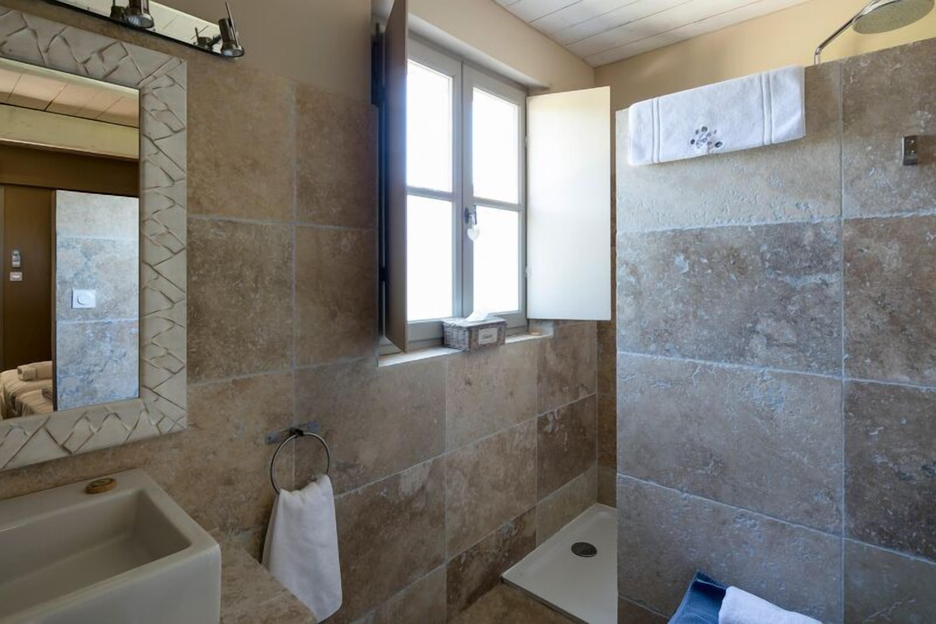 A bathroom with a bathtub, a window, and a shower area.