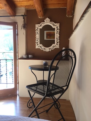 A small dining area with a black metal chair and table, a decorative mirror, and a window with a view of trees. - B&B Il Tulipano (Ricco del Golfo di Spezia)