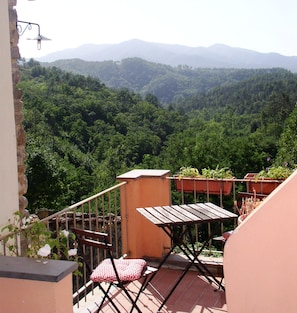 A balcony with a table and chairs, overlooking a forested valley and distant mountains. - B&B Il Tulipano (Ricco del Golfo di Spezia)