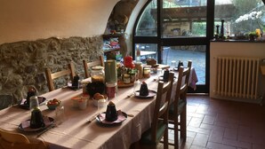 A dining area with a stone wall, a large arched window, and a view of a river. - B&B Il Tulipano (Ricco del Golfo di Spezia)