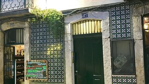 Un bâtiment avec une façade recouverte de carreaux, une porte verte et une enseigne publicitaire pour la vente de nourriture et de boissons.
