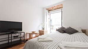 Une chambre avec un lit, une télévision, une petite table et une fenêtre.