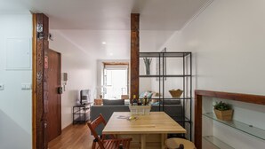 Un coin repas avec une table en bois, des chaises et une étagère en verre sur laquelle est posée une plante.
