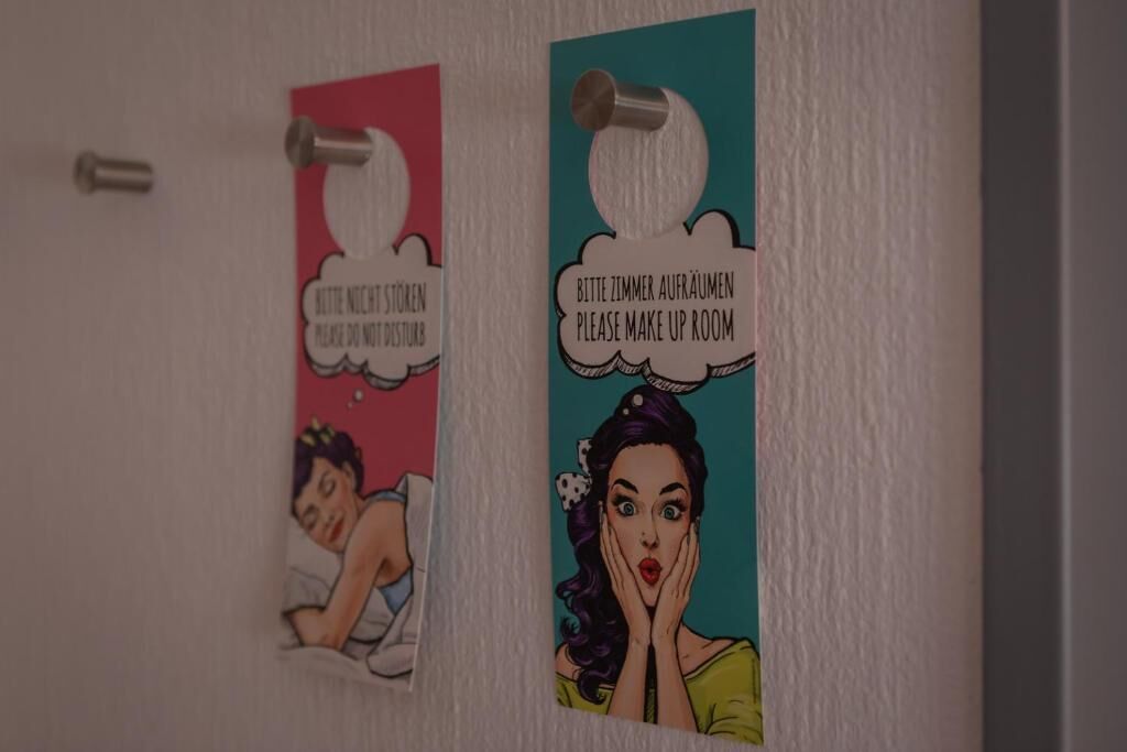 Two wall-mounted signs with text and illustrations, one in English and one in German, indicating a room for makeup.