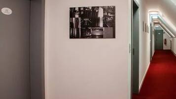 A hallway with a red carpet, a black and white artwork on the wall, and a door with the number 22.