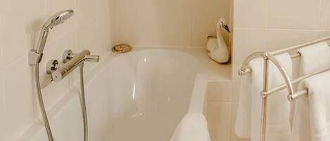 A modern bathroom with a bathtub, a handheld showerhead, and a towel rack with towels.