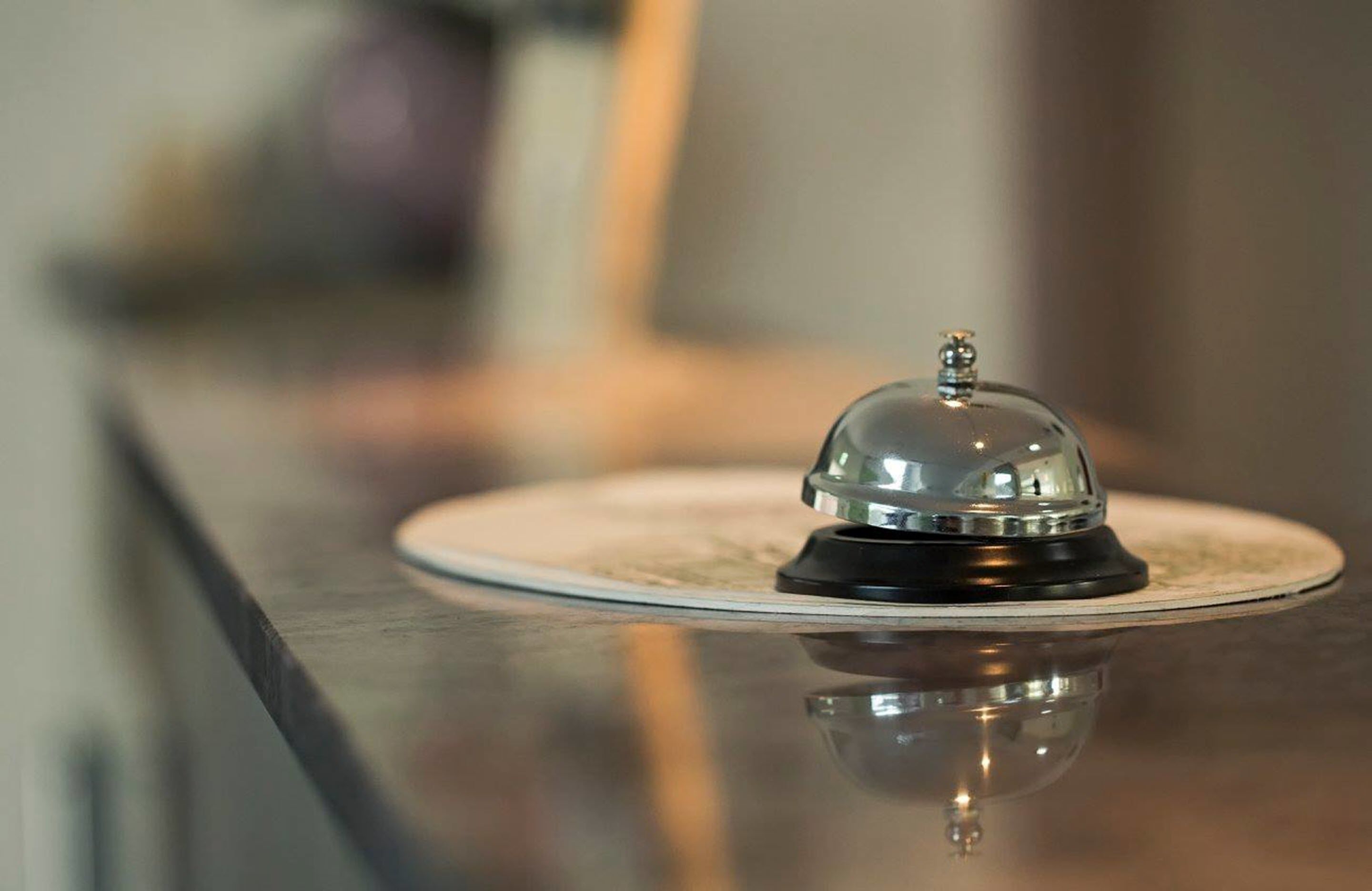 A hotel reception area with a reflective surface and a service bell.